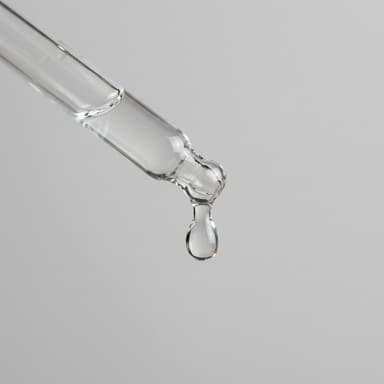 Precision glass dropper pipette releasing clear serum droplet